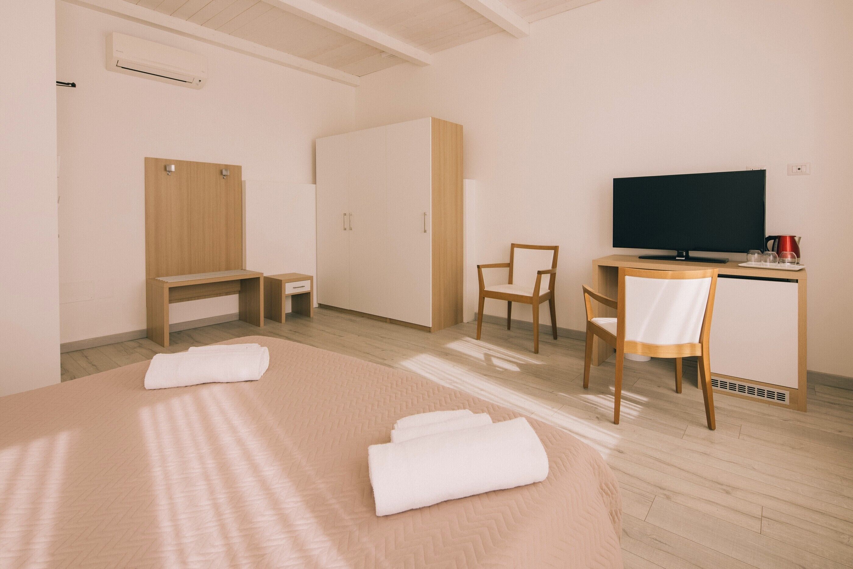 Una habitación de hotel con una cama, un escritorio con computadora, una silla, un televisor y un armario.