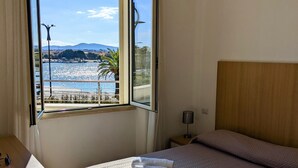 Une chambre d’hôtel équipée d’un lit, d’un bureau et d’une fenêtre donnant sur un plan d’eau et des montagnes.