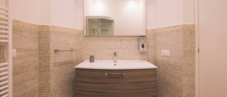 Un baño con un lavamanos blanco, un espejo encima y un salpicadero de azulejos.