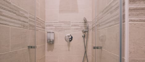 A shower with a handheld showerhead and a wall-mounted faucet.