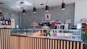 L’intérieur d’un café moderne, avec un comptoir en bois, une vitrine et des lampes suspendues.