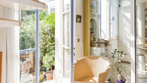 A bright room with large windows, a wicker chair, and potted plants. - Appt With Garden Near Jardin Du Luxembourg (Paris)