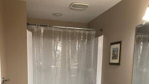 A bathroom with a shower curtain, toilet, sink, and cabinet.