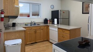 A compact kitchen with wooden cabinets, a dishwasher, a stove, and a refrigerator.