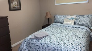 Ein Schlafzimmer mit einem Bett, einem Schminktisch, einer Lampe und einer Projektionsleinwand an der Wand.