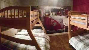 Una habitación con literas, un mural de una furgoneta Volkswagen roja y una cortina roja.
