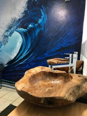 A bathroom with a large wave mural, a wooden sink, and a mirror. - The Vagabond Bunkhouse & Pizzaria - Hostel (Betws-Y-Coed)