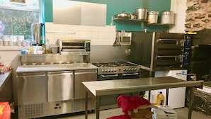 Una cocina industrial con electrodomésticos de acero inoxidable, un horno grande y un horno para pizza.
