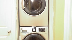 Pequeña lavandería de dos puertas con lavadora y secadora apiladas verticalmente.