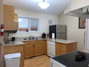 A compact kitchen with wooden cabinets, a dishwasher, a stove, and a refrigerator.