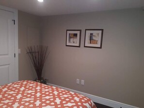 Une chambre à coucher avec une couvre-lit à motifs, une porte blanche et deux tableaux encadrés accrochés au mur.