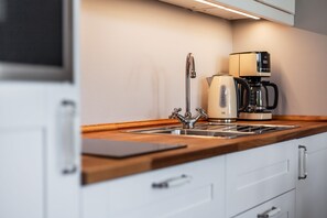 A modern kitchen with a stainless steel sink, a coffee maker, and a kettle.