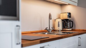 A modern kitchen with a stainless steel sink, a coffee maker, and a kettle. - App. Lolita - Lolita (Kühlungsborn)