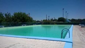 A swimming pool with a clear blue water surface, surrounded by a tiled deck area. - Hotel Menossi (Rio Cuarto)