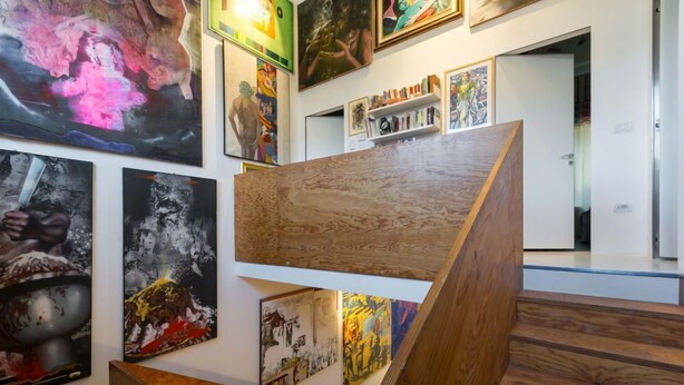 A gallery with various artworks on display, wooden staircases, and a bookshelf with books. - 3J Luxury Loft (Milan)