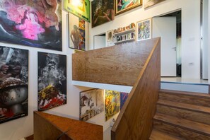 Eine Galerie mit verschiedenen Kunstwerken, Holztreppen und einem Bücherregal voller Bücher.