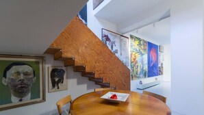 A dining area with a wooden table and chairs, a staircase with wooden steps, and artwork on the walls. - 3J Luxury Loft (Milan)
