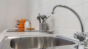 A stainless steel kitchen sink with a modern faucet, a kettle, and a utensil holder on the countertop. - Naviglio 89 Apartment (Milan)
