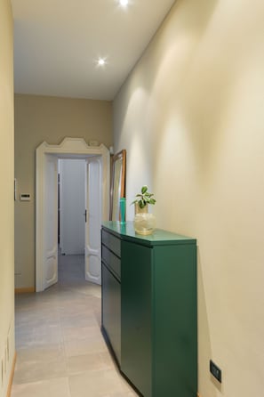 Ein Flur mit einem grünen Schrank, einem Spiegel und einer Topfpflanze.