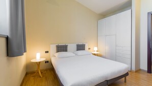 A bedroom with a bed, bedside tables, a wardrobe, and a light fixture. - Naviglio 89 Apartment (Milan)