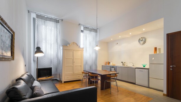 A modern living room with a sofa, TV, and dining area. - Naviglio 89 Apartment (Milan)