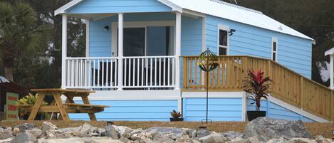 A blue house with a porch, a wooden staircase, and a picnic table.