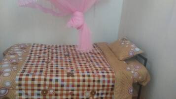 A bed with a checkered bedspread and matching pillows, a pink canopy, and a wall with a circular pattern.
