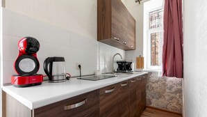 A modern kitchen with a white countertop, wooden cabinets, and a window with curtains. - Studio Apartment on top of old Tbilisi with a 180 degree View of the city (Dzveli Tbilisi)