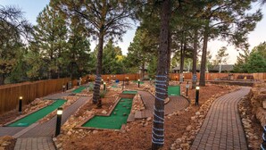 A miniature golf course with multiple lanes, wooden fences, and trees. - Luxurious Mountain View Golf Resort with tons of Amenities (Flagstaff)