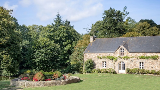 A stone house with a sloped roof, surrounded by lush greenery and a well-maintained lawn. - Manoir historique • domaine & étang • calme absolu (Pluduno)