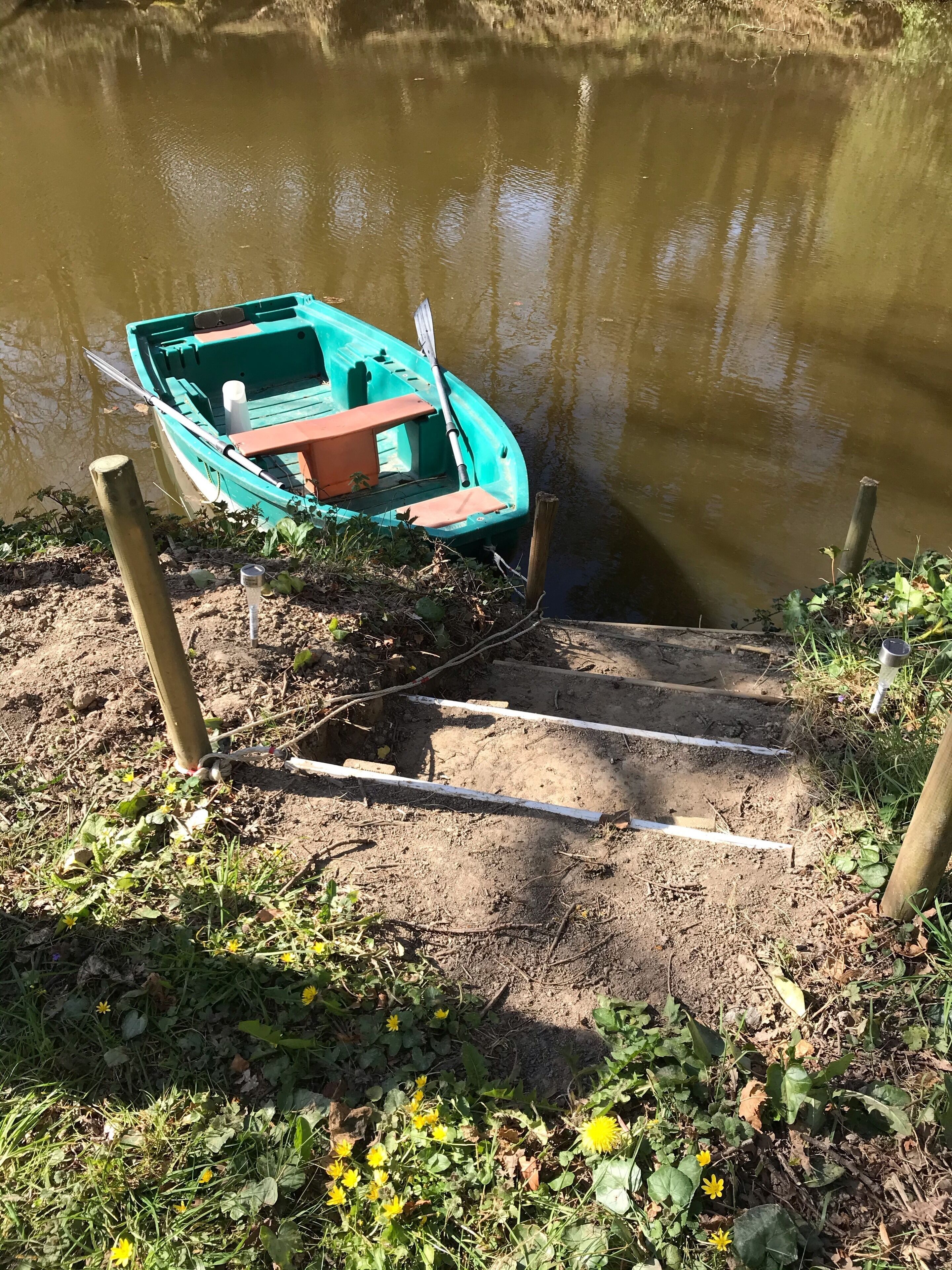Un petit bateau est amarré à un quai par un poteau en bois.