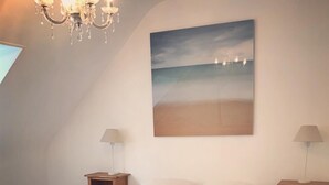 A bedroom with a large bed, two bedside tables with lamps, a chandelier, and a painting of a beach scene. - Manoir historique • domaine & étang • calme absolu (Pluduno)