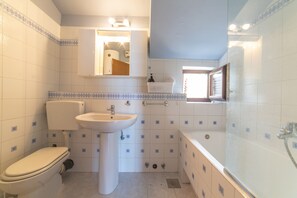 A bathroom with a toilet, sink, and bathtub. - Apartment Sunrise (Split)