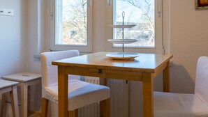 Ein kleiner Essbereich mit einem Holztisch und zwei weißen Stühlen. Auf dem Tisch steht eine dreistöckige, weiße Kuchenplatte.