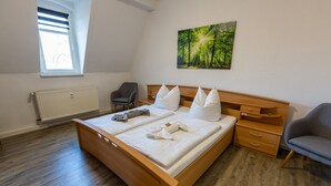 Ein Doppelbett mit weißer Bettwäsche, ein Holzkopfstück und ein Nachttisch mit Lampe.