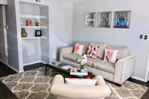 A living room with a sofa, coffee table, and a bookshelf. - 2 Bedroom Apartment near OU (Norman)