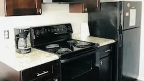 A kitchen with dark wooden cabinets, a black stove, and a black refrigerator. - 2 Bedroom Apartment near OU (Norman)