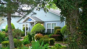 A house with a well-maintained garden, a mailbox, and a small front porch. - 2 Bedroom Apartment near OU (Norman)
