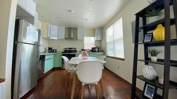 A compact kitchen with a refrigerator, stove, microwave, and a dining area with a table and chairs. - Eviestays Studio Close to OU, Downtown (Norman)