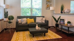 A modern living room with a grey sofa, yellow cushions, a patterned rug, and a coffee table. - Eviestays Studio Close to OU, Downtown (Norman)
