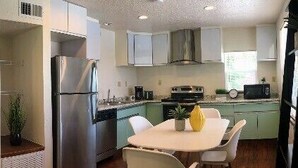 A modern kitchen with a dining area, stainless steel appliances, and light-colored cabinetry. - Eviestays Studio Close to OU, Downtown (Norman)