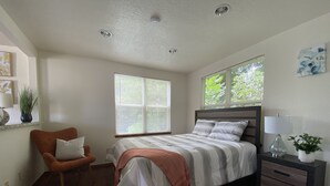 A bedroom with a bed, a chair, a nightstand, a window, and a ceiling light. - Eviestays Studio Close to OU, Downtown (Norman)