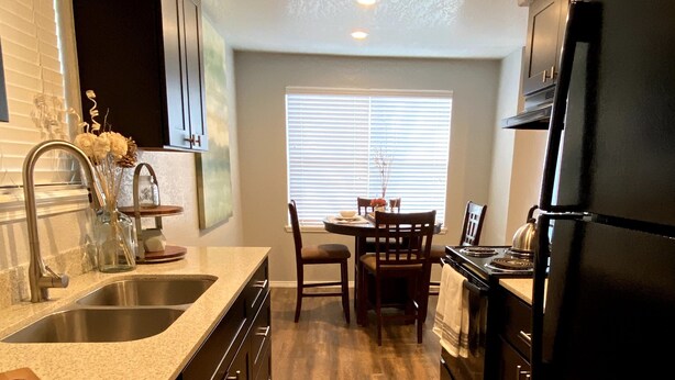A compact kitchen with a granite countertop, stainless steel sink, and a black refrigerator. - Evie's Campus-close 2 bedroom luxury (Norman)