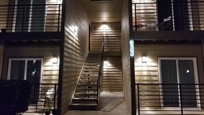 A multi-story building with a central staircase, balconies, and exterior lighting. - Evie's Campus-close 2 bedroom luxury (Norman)
