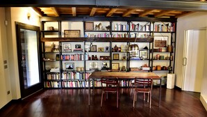 A spacious room with a large wooden table and chairs, surrounded by bookshelves filled with books and decorative items. - navigli design week apartment (Milano)