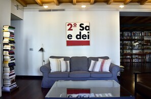 A living room with a grey sofa, a coffee table, and a bookshelf filled with books.