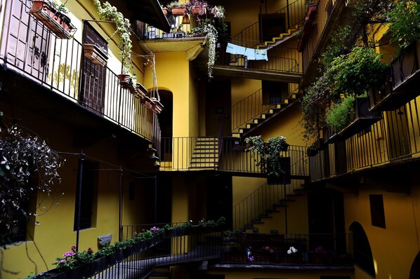 A multi-story building with balconies, some with plants and flowers.