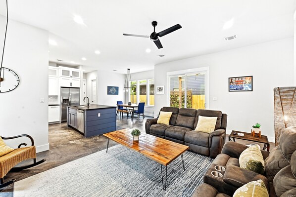 A modern living room with a sofa, coffee table, and a dining area in the background.