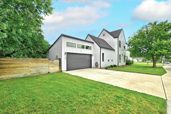 A modern two-story house with a garage, a well-maintained lawn, and a wooden fence.