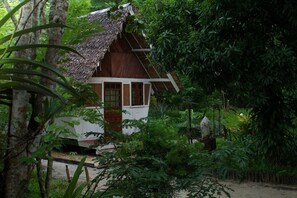 A small, thatched-roof structure surrounded by dense foliage. - Les Acacias Bungalows Manambato (Brickaville)